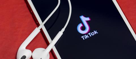 TikTok-Logo auf einem Smartphone mit Kopfhörern.