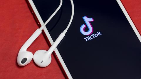 TikTok-Logo auf einem Smartphone mit Kopfhörern.