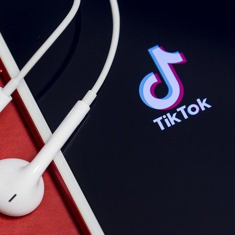 TikTok-Logo auf einem Smartphone mit Kopfhörern.