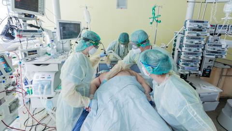 Intensivpflegekräfte und eine Ärztin (hinten) versorgen einen Corona-Patienten, der beatmet auf einer Intensivstation im Universitätsklinikum Bonn liegt (Archivbild).