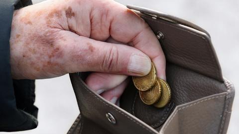 Eine ältere Frau am holt Münzen aus ihrem Portemonnaie.  ()