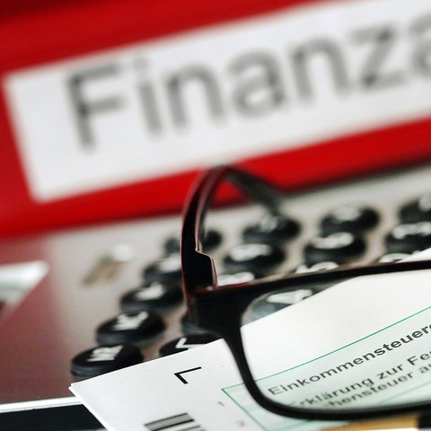 Auf einem Vordruck für die Steuererklärung liegt vor dem Aktenordner mit dem Aufdruck "Finanzamt" ein Stift und eine Brille.  (dpa)