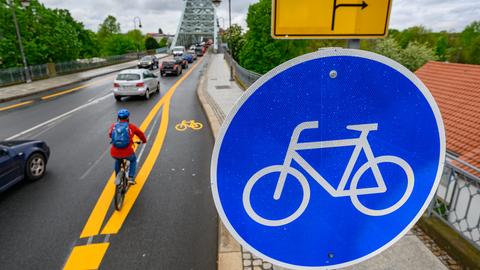 Ein Radfahrer fährt an der Elbbrücke Blaues Wunder auf einem markierten Radweg.