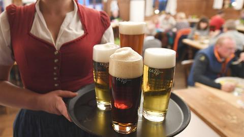 Eine Bedienung hält, in einem Wirtshaus, ein Tablett voll mit Bier.  (picture alliance/dpa)