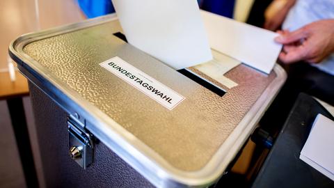 Ein Wähler wirft in einem Wahllokal seinen Stimmzettel für die Bundestagswahl 2021 in eine Wahlurne.  (dpa)