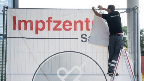 Ein Banner mit der Aufschrift "Impfzentrum Sachsen" wird von einem Bauzaun entfernt (dpa)