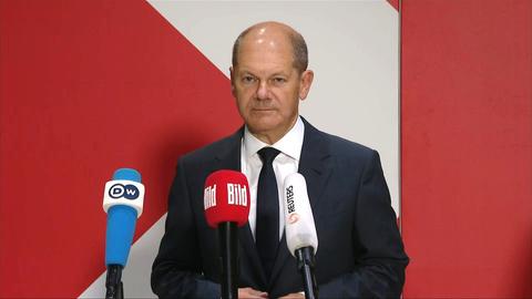 Olaf Scholz steht hinter drei Mikrofonen während eines Statements vor Medienvertretern. ()