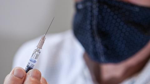 Ein Arzt hält während der Corona-Pandemie eine Spritze mit einer Grippeimpfung in der Hand. (dpa)