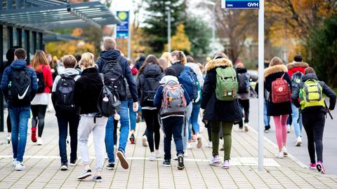 Schulkinder laufen in einer Gruppe an einer Bushaltestelle vorbei. (dpa)