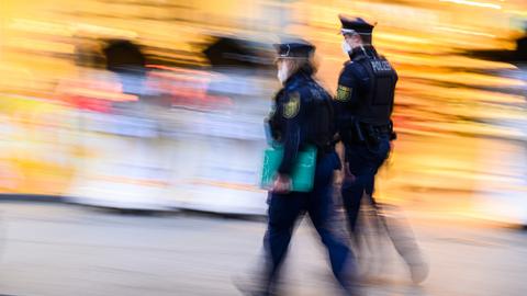Polizisten laufen auf der Einkaufsmeile Prager Straße vor Geschäften entlang. Die Polizeidirektion Dresden kontrolliert die Einhaltung der neuen Corona-Regeln täglich mit 50 Beamtinnen und Beamten. (dpa)