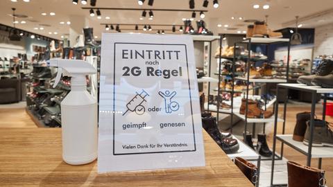 Ein Hinweisschild mit der Aufschrift "Eintritt nach 2G Regel geimpft oder genesen" steht am Eingang eines schuhgeschäfts in Norderstedt (dpa)