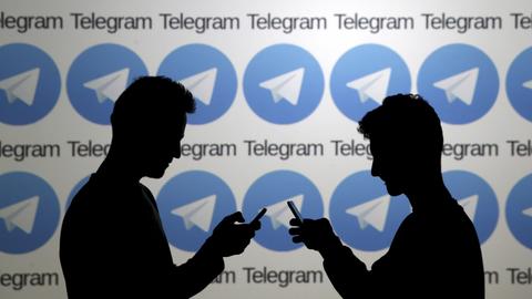 Zwei Mobilfunknutzer vor einer Wand mit Logos des russischen Messengerdienstes Telegram (REUTERS)