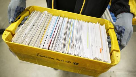Eine Mitarbeiterin der Deutschen Post trägt eine Kiste mit Briefen (dpa)