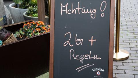 Ein Hinweisschild mit Aufschrift "Achtung! 2G+ Regel" steht vor einem Restaurant. (dpa)