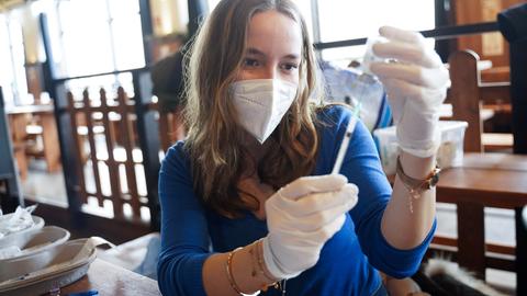 Eine Medizinstudentin bereitet eine Spritze für eine Corona-Impfung in einer Einrichtung für Obdachlose in Berlin vor.  (dpa)