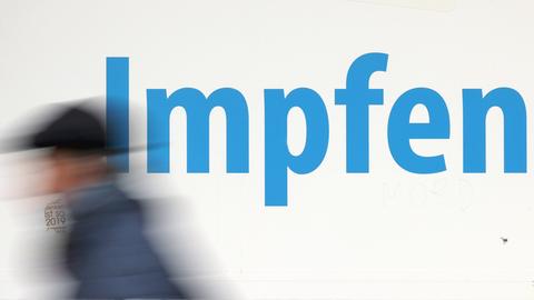 Ein Mann eilt an einem Platkat mit der Aufschrift "Impfen" vorbei. (picture alliance/dpa)