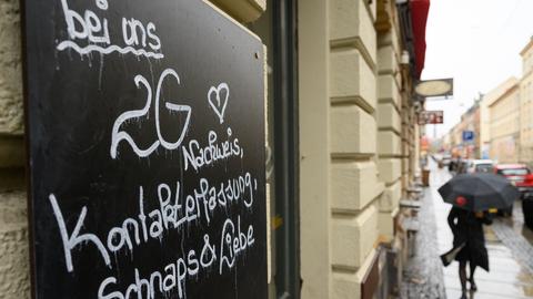 : "Bei uns 2G Nachweis, Kontakterfassung, Schnaps & Liebe" steht auf einem Schild an einer Bar in der Dresdner Neustadt (dpa)