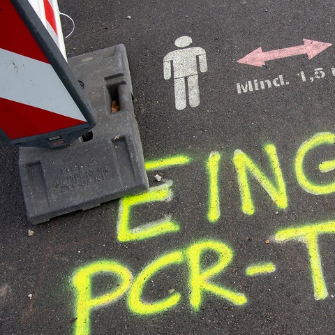 Die Worte "Eingang PCR-Test" sind mit gelber Farbe am Eingang vor einem Corona-Testzentrum auf die Straße gemalt worden. (dpa)