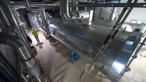 Ein Mitarbeiter der EnBW läuft im Neubau des Gaskraftwerkes Gaisburg an einem Wärmeüberträger vorbei.  (dpa)