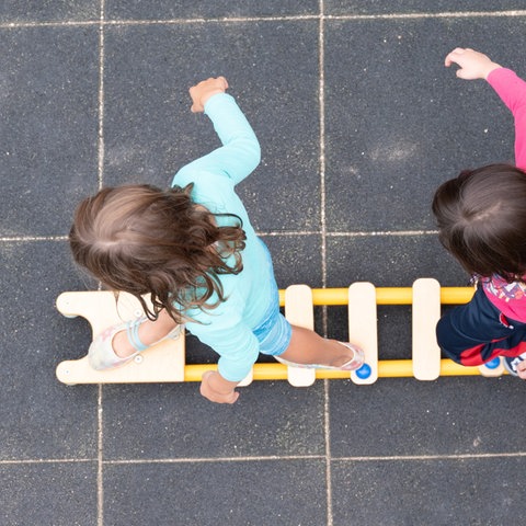 Kinder balancieren auf dem Spielplatz einer Kindertagesstätte im sächsischen Dresden auf einem Brett. (dpa)