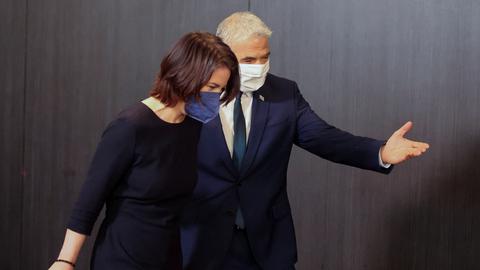 Bundesaußenministerin Annalena Baerbock und Israels Außenminister Jair Lapid auf dem Weg zur gemeinsamen Pressekonferenz im Februar 2022. Beide tragen Corona-Schutzmasken. (REUTERS)