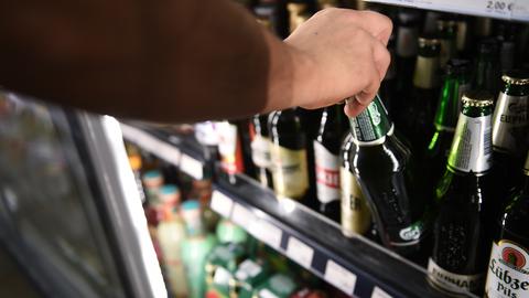 Ein Mann holt eine Flasche Bier aus einem Kühlschrank in einem Spätkauf. (dpa)