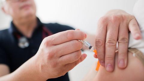 Ein Arzt gibt eine Impfung: Hände halten eine Spritze, die in einen Arm sticht (picture alliance/dpa)