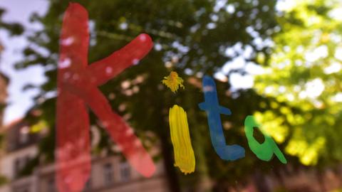 Der bunte Schriftzug "Kita" ist in München mit Fingerfarbe auf die Fensterscheibe einer Kindertagesstätte gemalt (Archivbild) (dpa)