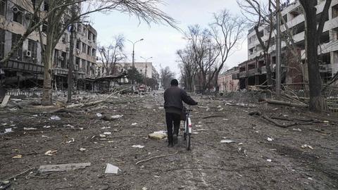 Ein Mann geht mit seinem Fahrrad durch eine zerstörte Straße im ukrainischen Mariupol (AP)