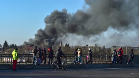 Fußgänger stehen auf einer Überführung in Lwiw und schauen auf eine Rauchwolke in der Nähe. (dpa)