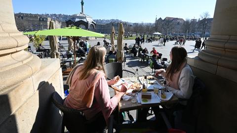 Bei strahlendem Sonnenschein sitzen Passanten in einem Straßencafe in Stuttgart (dpa)