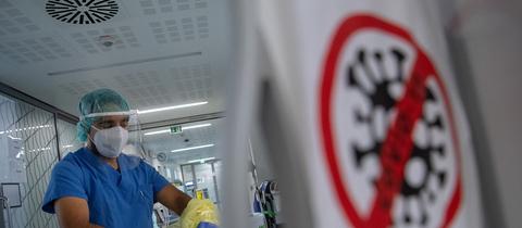Ein Pfleger zieht beim Verlassen der Intensivstation für Corona-Patienten am Sana Klinikum Offenbach seinen Schutzkittel aus.  (dpa)