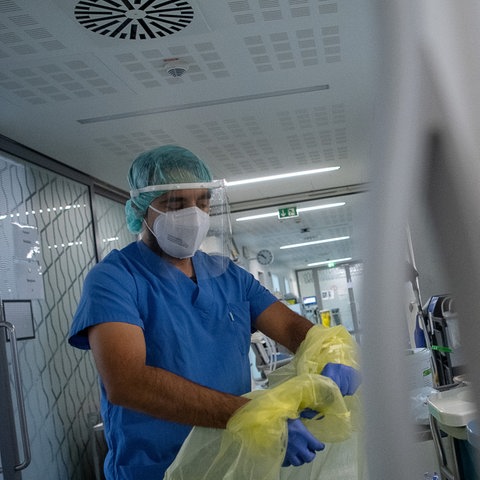 Ein Pfleger zieht beim Verlassen der Intensivstation für Corona-Patienten am Sana Klinikum Offenbach seinen Schutzkittel aus.  (dpa)