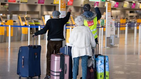 Ein Mann mit einer Weste mit Verdi-Schriftzug spricht im Terminal 1 des Flughafens Frankfurt mit Reisenden.  (dpa)