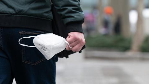 Ein Mann hält eine FFP2-Maske in der Hand. (dpa)