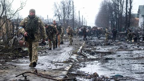 Ukrainische Soldaten inspizieren die Trümmer einer zerstörten russischen Panzerkolonne auf einer Straße in Butscha. (dpa)