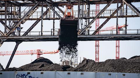 Ein Bagger entlädt Kohle von einem Binnenschiff auf eine Halde neben einem Kraftwerk in Offenbach. (dpa)
