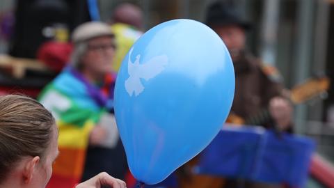 Einen Luftballon mit einer Friedenstaube hält eine Frau in der Hand beim Ostermarsch auf dem Anger.  (dpa)