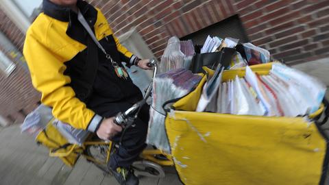 Ein Postbote fährt mit seinem Fahrrad die Post aus. (picture alliance / dpa)