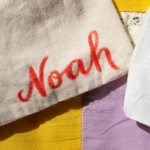 Stoffbeutel mit den Namen "Noah" und "Emilia" liegen nebeneinander. (dpa)