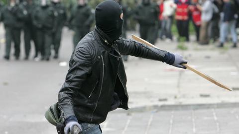 Ein vermummter Demonstrant wirft einen Stein in Richtung Polizei. (picture alliance / ASSOCIATED PR)