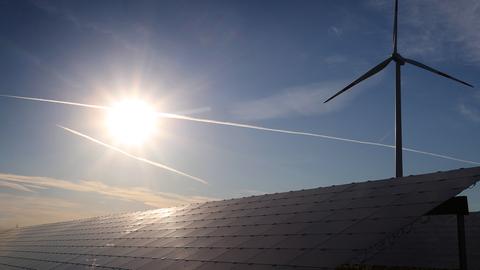 Ein Windrad steht hinter den Solarzellen einer Solarkraftanlage im Sonnenschein. (picture alliance/dpa)