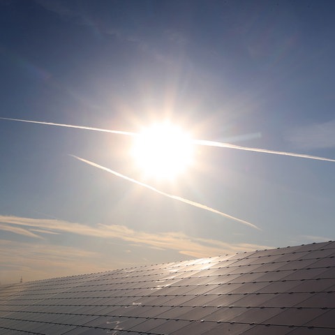 Ein Windrad steht hinter den Solarzellen einer Solarkraftanlage im Sonnenschein. (picture alliance/dpa)