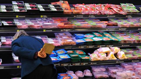 Eine Frau steht vor einem Supermarktregal mit abgepacktem Fleisch (dpa)