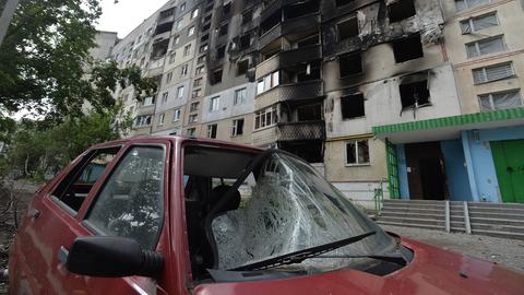 Ein zerstörtes Auto steht vor einem beschädigtem Gebäude in Charkiw (Ukraine). (dpa)