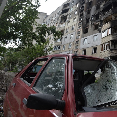 Ein zerstörtes Auto steht vor einem beschädigtem Gebäude in Charkiw (Ukraine). (dpa)