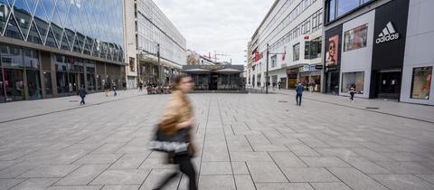 Eine Frau läuft durch eine nahezu leere Einkaufsstraße in Frankfurt. (dpa)