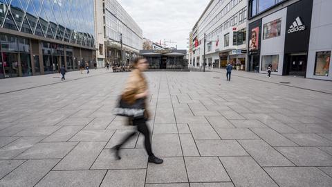 Eine Frau läuft durch eine nahezu leere Einkaufsstraße in Frankfurt. (dpa)