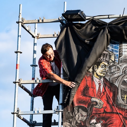 Ein Mitarbeiter der documenta fifteen verhüllt ein großflächiges Banner des Kollektivs Taring Padi.  (dpa)