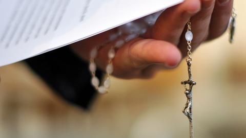 Ein Priester hält einen Rosenkranz und eine bischöfliche Erklärung zu den Missbrauchsfällen durch Jesuiten-Pater in der Hand. (dpa)